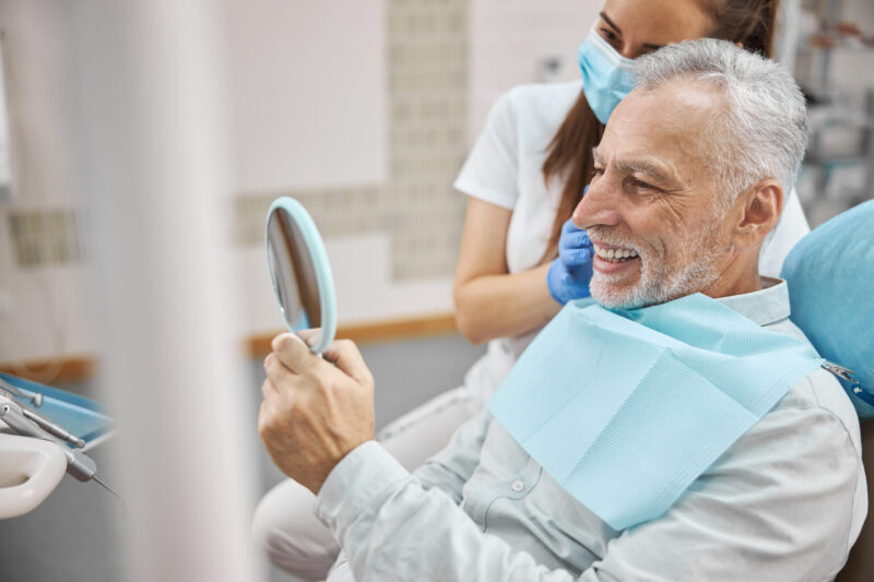 patient looking at his teeth after having dental implants