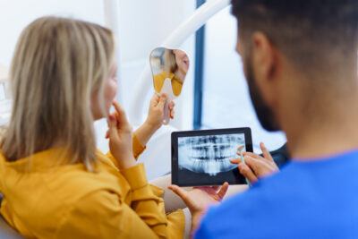 woman looking at her teeth after dental implant procedure, dentist showing her the x-ray