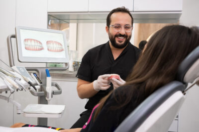 orthodontist examining a woman's teeth and explaining the Invisalign treatment plan 