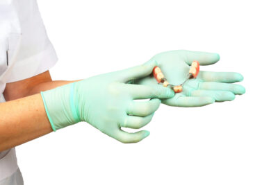 dentist holding a dental bridge in hand with gloves 