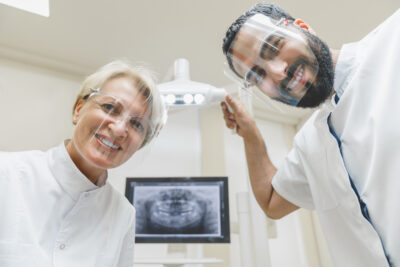 dentist looking at patient's mouth - they are checking the dental implants 