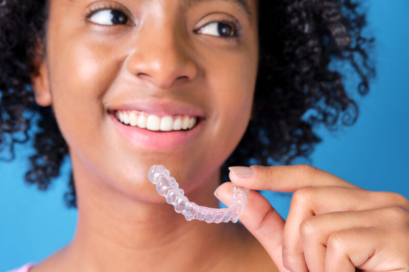 young woman holding her Invisalign retainer